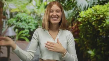 Canlı, yeşil yeşilliklerle dolu bir parkta gülümseyen bir kadın, mutluluk saçıyor ve neşeli bir tavır sergiliyor..