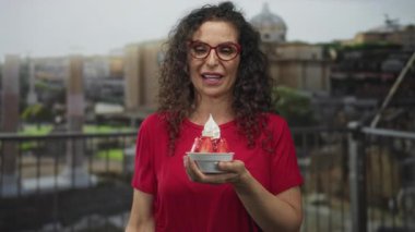 Kadın tatlı kasesini çırpılmış krema ve çilek dilimleriyle tutuyor..