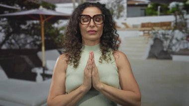 Kıvırcık saçlı, gözlük takan ve dua ederken el ele tutuşan kadın bina girişinde iç huzuru buldu..