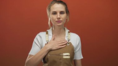 Göğüs göğüse söz veren, önlük giyen, canlı kırmızı arka plana karşı duran, samimiyet ve bağlılığı somutlaştıran, dürüstlük ve adanmışlık teması için mükemmel bir kadın..