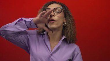 Kırmızı stüdyoda transseksüel İspanyol kadın gözlük takıyor ve ağızla bağırıyor..