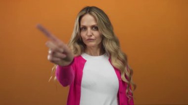 Bir kadın duvara bakarken parmağını tutar ve boş çerçevenin üzerinde izole edilmiş turuncu arka planda genç sarışın bir deneği resmeder..