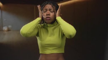 Stüdyoda elleri ve kulakları olan, yeşil ekinlerle örülmüş saçlar, gözleri kapalı ve buruşmuş, kulak ağrısı çeken bir kadın..