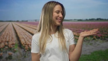 Gülen kadın lale tarlasında çiçek tutuyor.