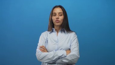 Çapraz kollu bir kadın ve stüdyoda mavi perde arkası ve açık gömlekli, gözleri kapalı, kendine güveni tam bir kadın..