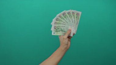 Para, el ve banknotlara odaklanmış yeşil bir zemin üzerinde Singapur dolar tutan adam izole bir ortamda.