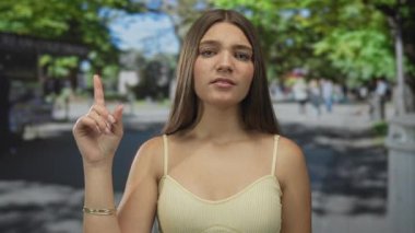 Kolsuz tişörtlü beyaz kız, kalabalık şehir caddesinde onaylanmamış jest gösteriyor..