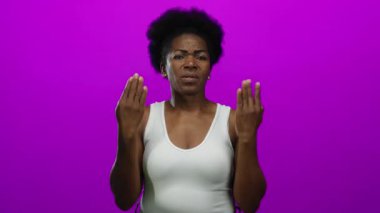 Afrika kökenli Amerikalı bir kadın, pembe bir arka plana karşı elleri açık hayal kırıklığını ifade ediyor..