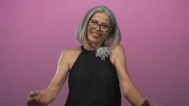 Uzanmış kolları ve açık elleri olan bir kadın stüdyoda pembe arka planla öne uzanıyor; sıcaklık bağlantı açıklığı.