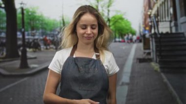 Kot önlüklü kadın aşağı bakarken kaldırım taşı sokağında sağı işaret ediyor..