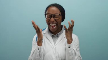 Steteskoplu beyaz önlüklü gülümseyen Afrikalı kadın arka planda sevinçle kutlama yapıyor.