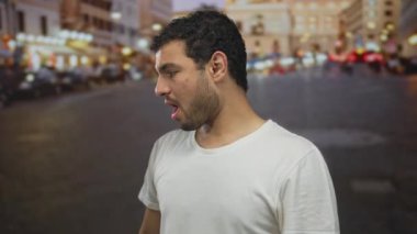 Beyaz tişörtlü adam ellerini başının üstüne kaldırır ve kalabalık bir caddede gece gözlerini korur. Sürpriz!.