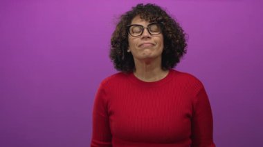 Gözleri kapalı ve kafası stüdyoda canlı mor arka plana yaslanmış bir kadın; dinginlik farkındalığı.