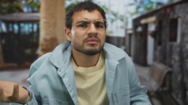 Latin kökenli genç adam, kenar mahalle ve ağaçlarla el sıkışma hareketi yapıyor..