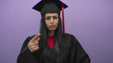 Mezuniyet üniformalı İspanyol kadın mor duvara karşı fikir ayrılığını dile getiriyor..