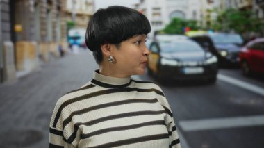 Kalabalık bir caddede arka planda arabalarla gülümseyen ve işaret eden bir kadın..