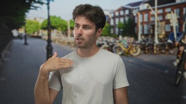 Park halindeki bisiklet ve elektrik direkleriyle şehir caddesinde el hareketi yapan bir adam; belirsizlik tefekkür.