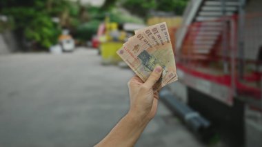 Bir şehir caddesinde elinde Romen leu banknotları tutan adam, gündelik bir ortamda Romanya para birimi üzerinde yoğunlaşarak kentsel açık hava finansmanının özünü yakalıyor..