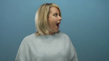 Yan profilde gri süveter giyen genç sarışın bir kadın stüdyoda ağzı açık soluk soluğa jest yaparken görülmüş. Sürpriz..
