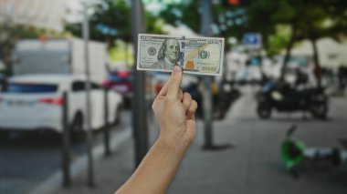 Şehir sokaklarında Amerikan dolarlarını elinde tutan bir adam araçları ve bulanık arka plan sergilenen finans ve ekonomi ile şehir merkezinde.