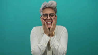 Gözlük takan bir kadın şakacı ifadesini sergileyen bir sette iki eliyle yanakları birbirine bastırıyor..