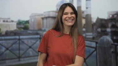 Roma harabelerinin önünde gülümseyen genç bir kadın, arka planda sütunları ve tarihi mimarisi olan açık şehir ortamında canlı bir mirası simgeliyor..