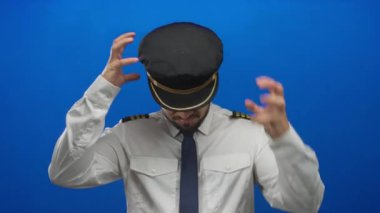 Mavi arka planda stresi olan genç İspanyol pilot, havacılık kıyafeti ve duygularla mücadele ediyor..