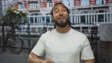 Yumruklarını sıkan adam binanın önünde tezahürat yapıyor ve gülümsüyor..