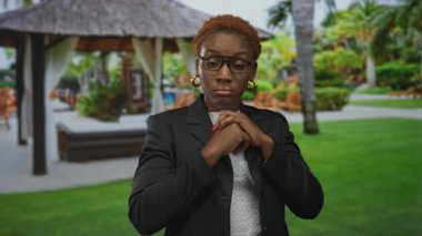 Gözlüklü ve spor ceketli bir kadın gün ışığında iki eliyle bir binanın duvarını kapatıyor. Sürpriz..