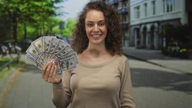 Kadın elinde dolarlarımızın hayranı, güler yüzlü ve paralı bir şekilde şehir sokaklarındaki paralara bakıyor..