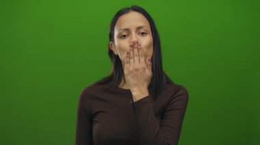 Genç İspanyol kadın yeşil izole bir arka planda neşeli bir pozla öpüşüyor.