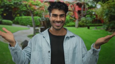 İspanyol adam gülümserken bir binanın önünde kollarını açıyor; sevinç iyimserliği kutlaması.