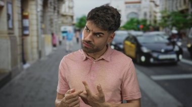 Kalabalık şehir caddesinde, yoğun trafiğin ortasında, çatık kaşlarla dikkatle bakan adam parmaklarına güveniyor; karmaşa.