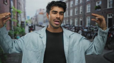 Tuğla binalar ve park edilmiş bisikletlerle çevrili hareketli şehir caddesinde el kol hareketi yapan adam, hevesli iletişim.