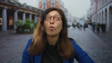 Orta yaşlı İspanyol kadın gün ışığında şehir caddesinde yukarı bakarken dudaklarını büzüyordu..