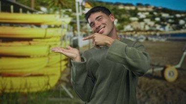 Adam kumlu sahildeki sarı kano sırasının yanındaki kumsalı işaret ediyor; kanoyu keşfetme daveti.