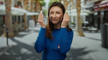 Mavi gömlekli genç bir kadın Amerika 'nın güneşli bir caddesinde komik suratlar yapıyor..