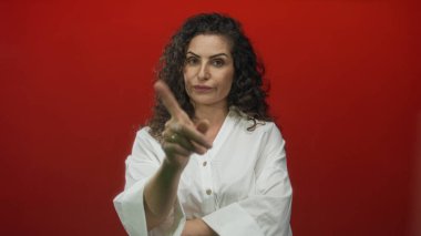 Beyaz gömlek yaka üzerinde işaret parmağı ile çene dokunan ve stüdyoda dinlenme pozisyonu tutan kadın; düşünceli yansıma içgörü.