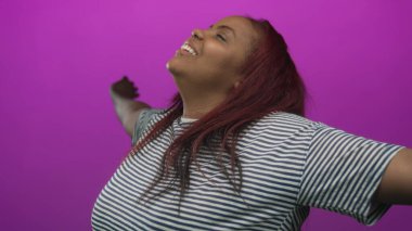 Kollarını genişçe açan bir kadın ışıldayan bir gülümseme ile, yüzü yukarı döndü ve uzun kızıl saçlı mor bir stüdyo; sevinç;.