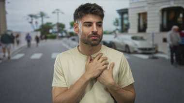 Arabaların ve bulanık yayaların yanında güneşli bir şehir sokağında göğsüne sarılan adam, minnettarlık..