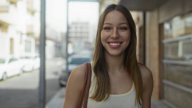 İspanyol kadın omuzlarını açmış gülümsüyor ve bir şehir caddesinde sağına bakıyor; iyimserlik.