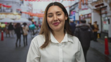 Crisp beyaz gömlekli genç İspanyol kadın kırmızı fener süslemeleri altında kalabalık şehir caddesinde saçlarını kulaklarının arkasına sıkıştırıyor..