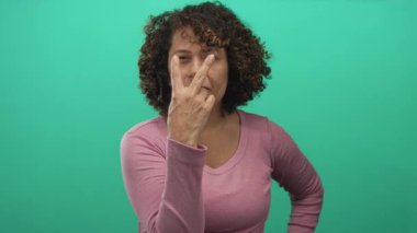 Stüdyoda işaret parmağıyla işaret parmağı gösteren kendinden emin orta yaşlı bir kadın..