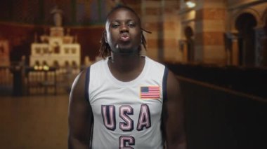 Amerikan bayraklı basketbol formasında dudak büzen bir adam Katolik kilisesinin içinde çıplak omuzlar, neşeli bir topluluk..