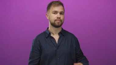 Avuç içi açık gösteren ve elini kaldıran genç bir adam, sanki stüdyoda mor arkaplanı olan bir nesne sunuyormuş gibi el hareketi yapıyor..