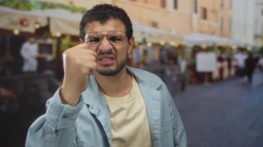 Genç İspanyol adam hareketli bir sokak pazarında renkli hatıraları incelerken burnunu çimdikliyor..