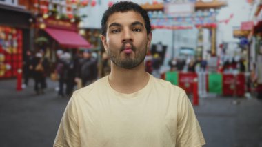 Gündüz vakti işlek bir şehirde sarı bir tişört giyen genç adam görünür dudaklarla gülümsüyor. Mutluluk..