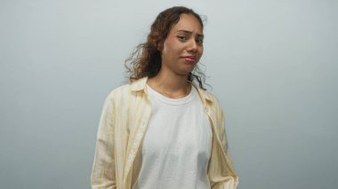 Suratını ve omuzlarını ekşiten, sarı çizgili gömlek ve beyaz t-shirt giyen bir kadın soluk mavi arka planda; huzursuz yansıma.