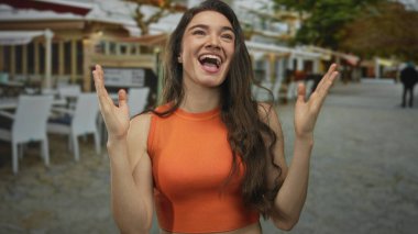 İspanyol kadın geniş bir gülümseme ve açık avuçlar ile ellerini kaldırıyor açık restoran terasında; saf neşe.