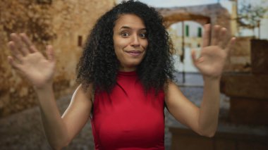 Kıvırcık saçlı, kırmızı uçlu bir kadın güneşli eski bir kasaba sokağında parmakları göğsüne kadar uzanan güven..